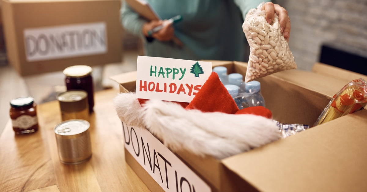 A close-up of a person grabbing a small bag of beans from a box with a sign on the side that reads "donation."