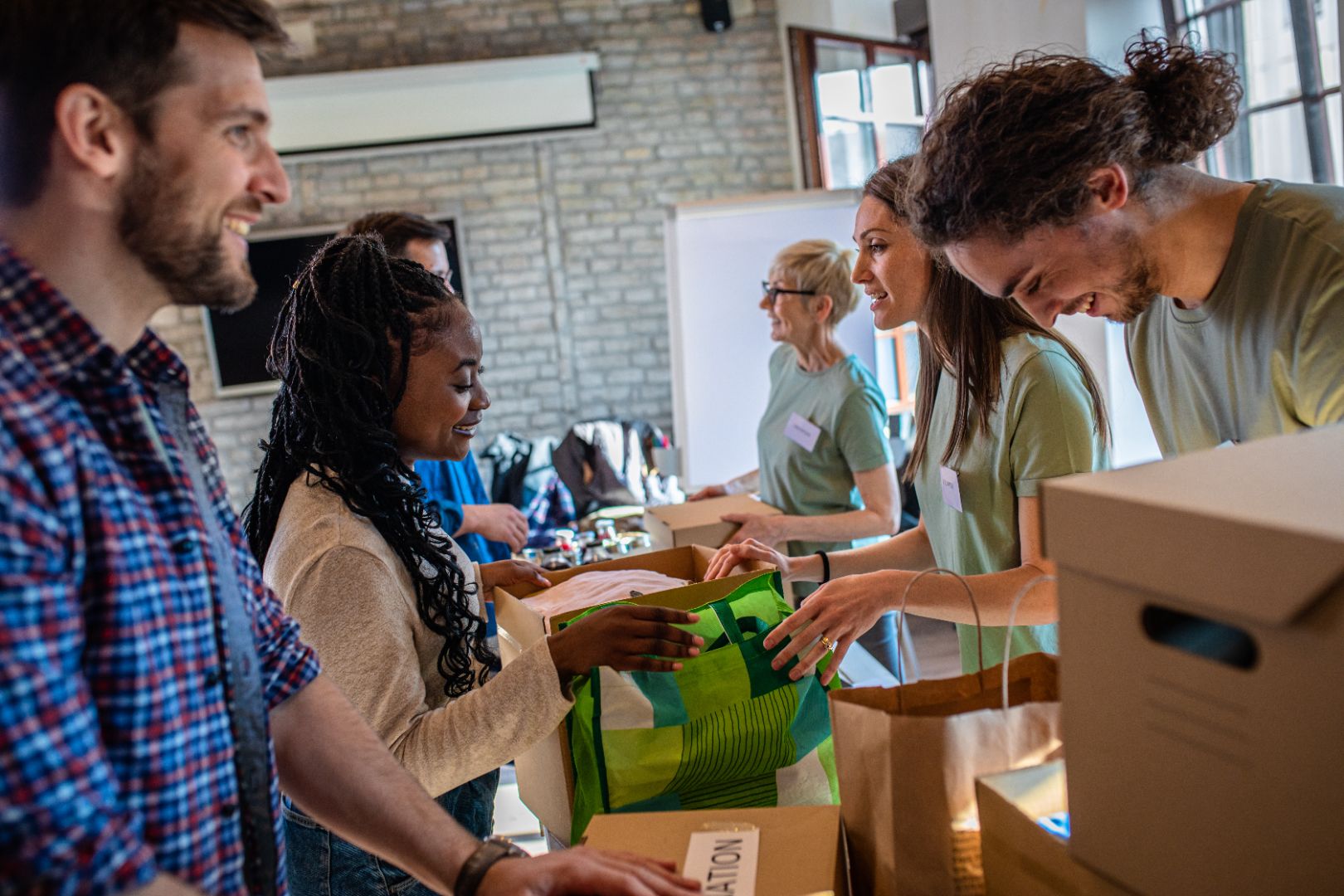 A group of volunteers are working at a community charity donation center. They’re boxing up items to send to a homeless center.